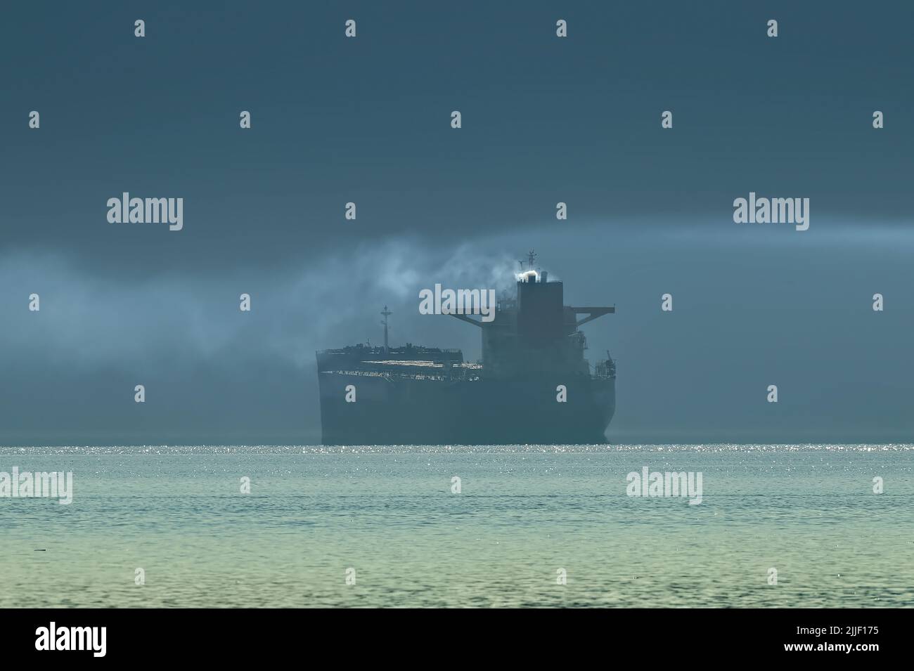 Ein Seeschiff, das Dieselrauch in die Luft vergieße, während es am Hafen von Vancouver auf seine Wende wartet. Stockfoto