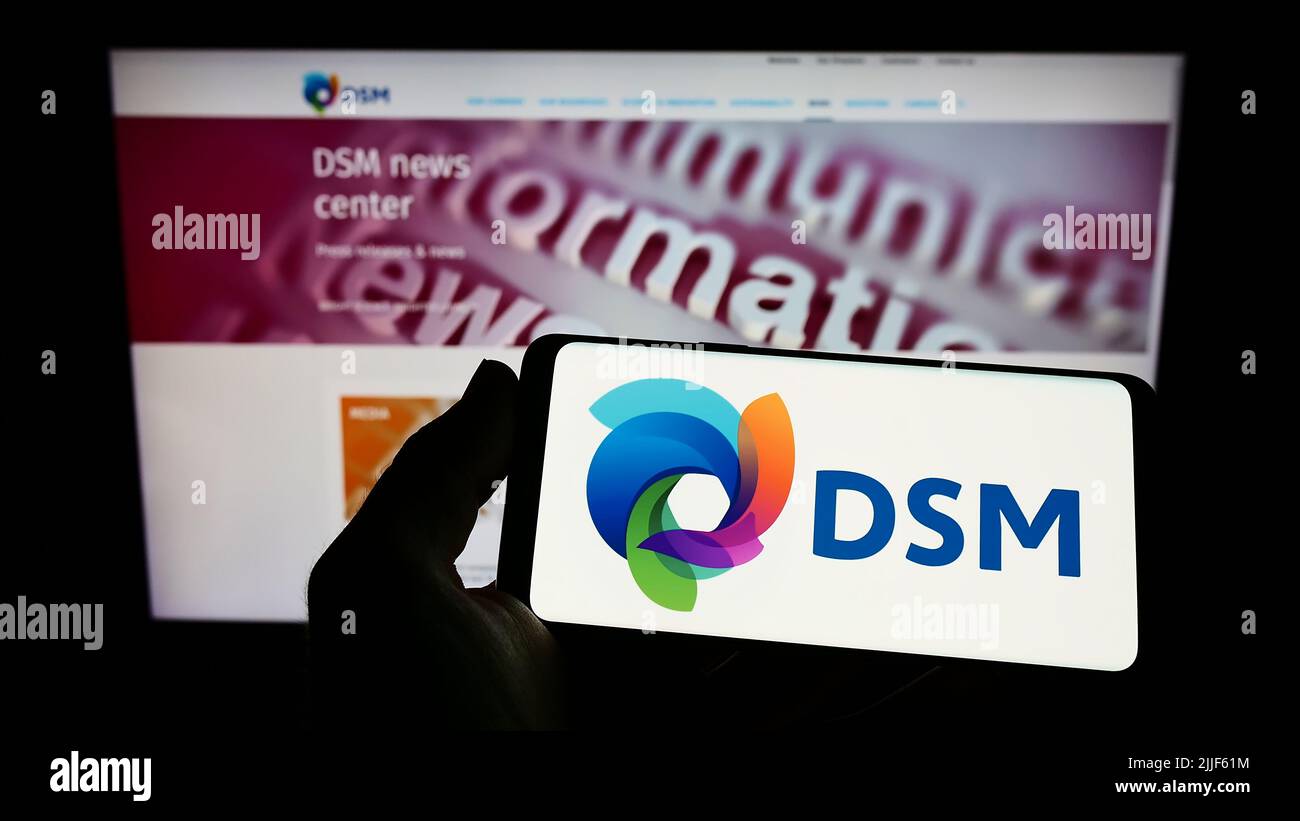 Person, die das Smartphone mit dem Logo des niederländischen Chemieunternehmens Koninklijke DSM N.V. auf dem Bildschirm vor der Website hält. Konzentrieren Sie sich auf die Telefonanzeige. Stockfoto