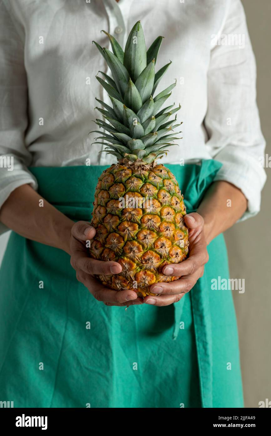 Weibliche Köchin hält eine Ananas, Nahaufnahme von Obst - Stock Foto Stockfoto
