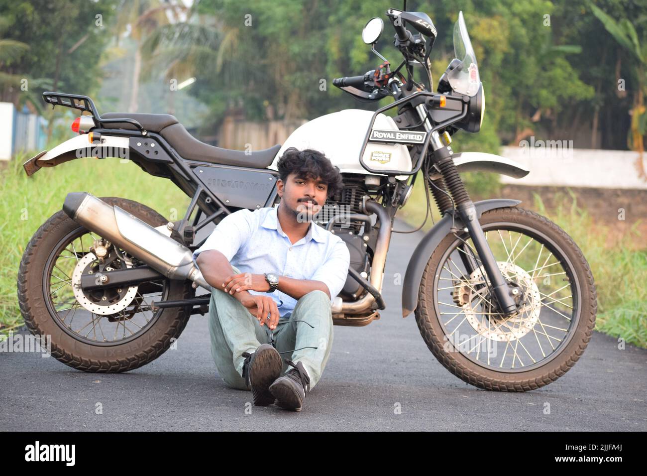 Ein indischer junger Mann, der auf einem Motorrad in der Nähe eines Reisfelds reitet Stockfoto