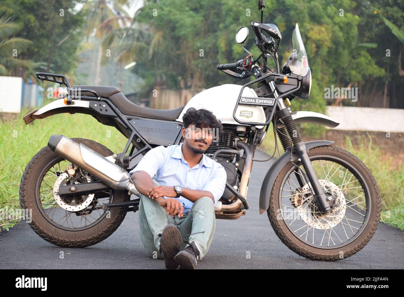 Ein indischer junger Mann, der auf einem Motorrad in der Nähe eines Reisfelds reitet Stockfoto