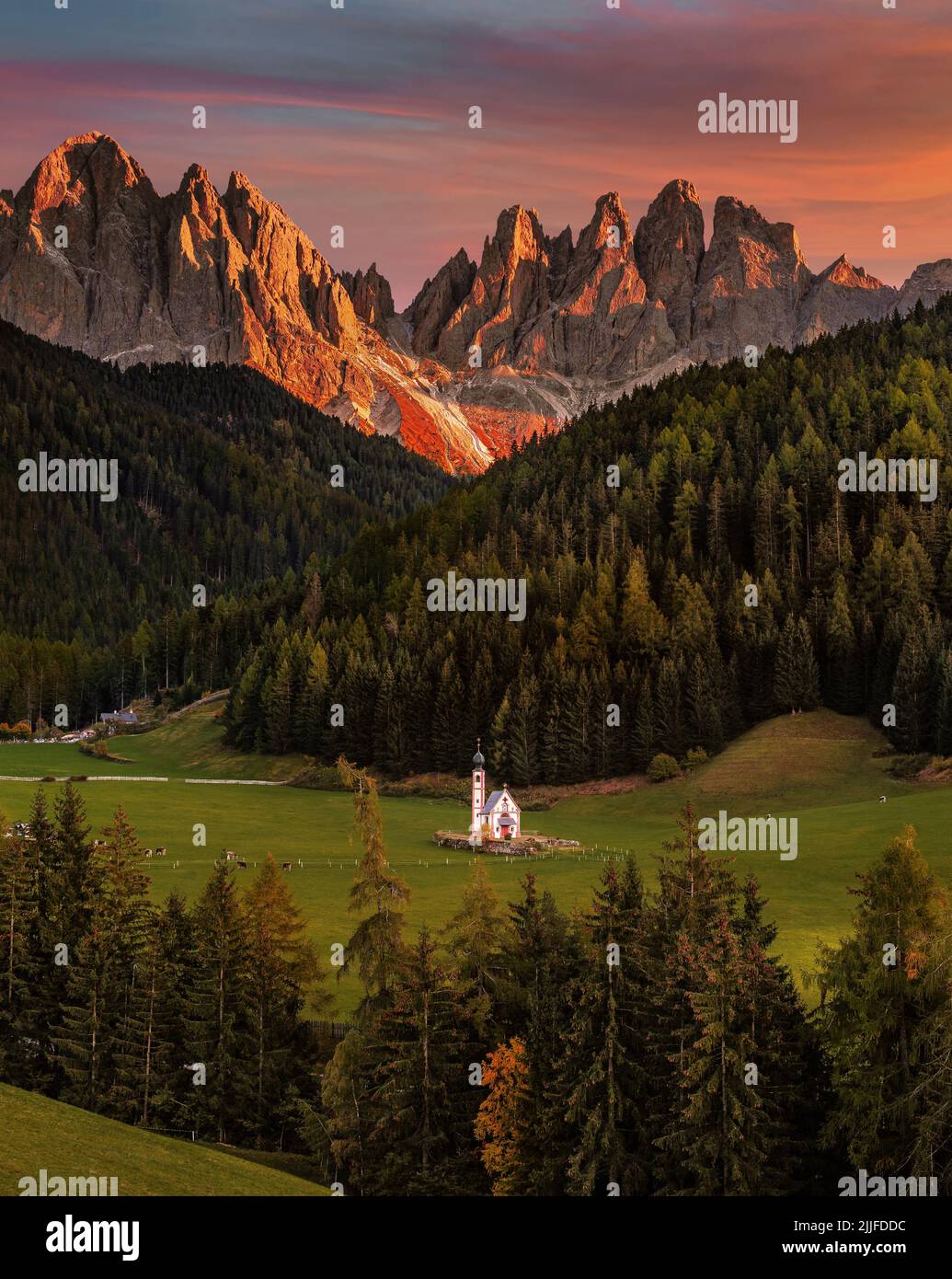 Val di Funes, Dolomiten, Italien - die wunderschöne St. Johann Kirche in Südtirol mit den italienischen Dolomiten und spektakulärem bunten Sonnenuntergang am Backgrou Stockfoto