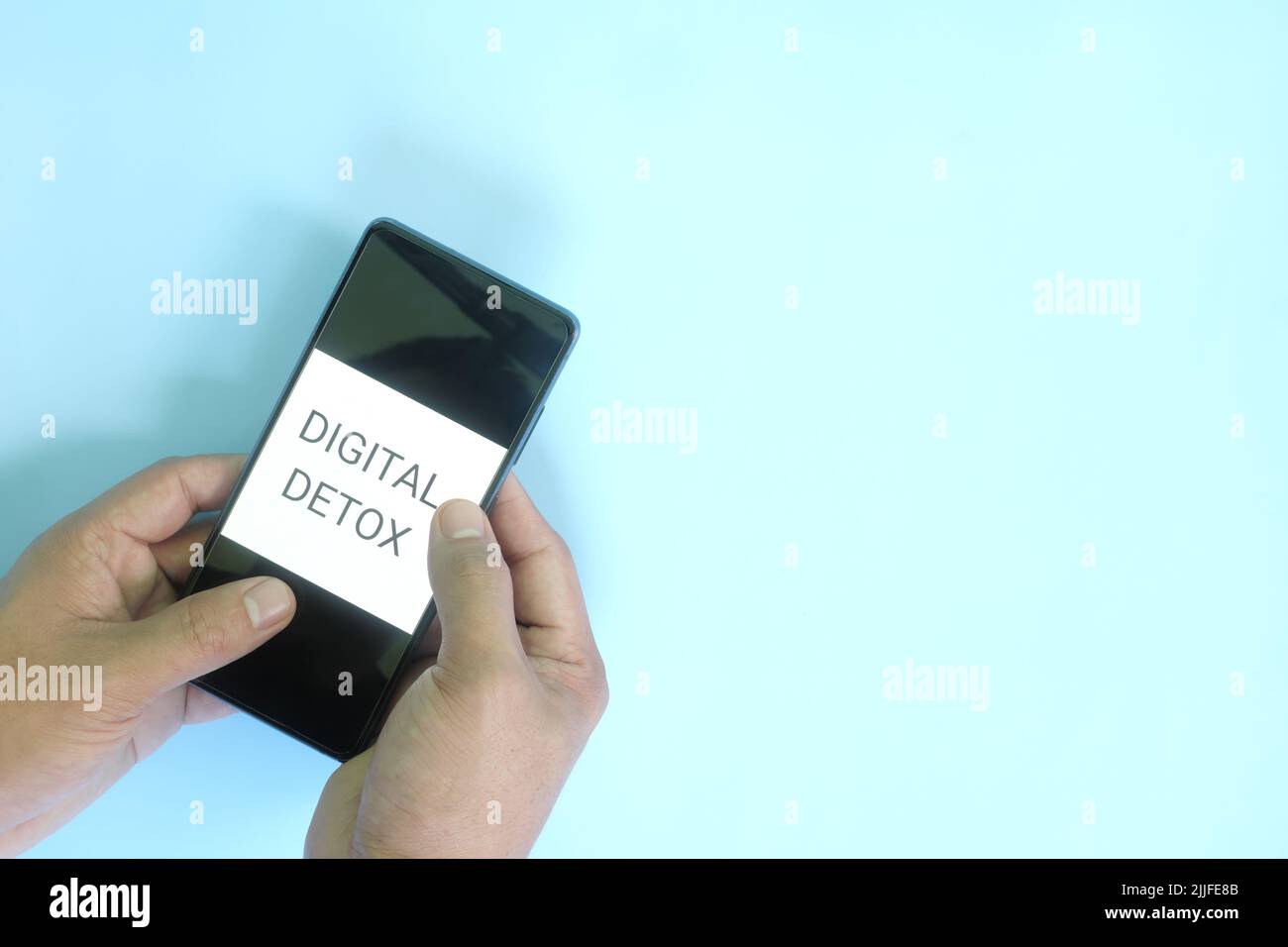 Digitales Detox-Konzept. Hand hält ein Mobiltelefon in blauem Hintergrund flach lag. Stockfoto