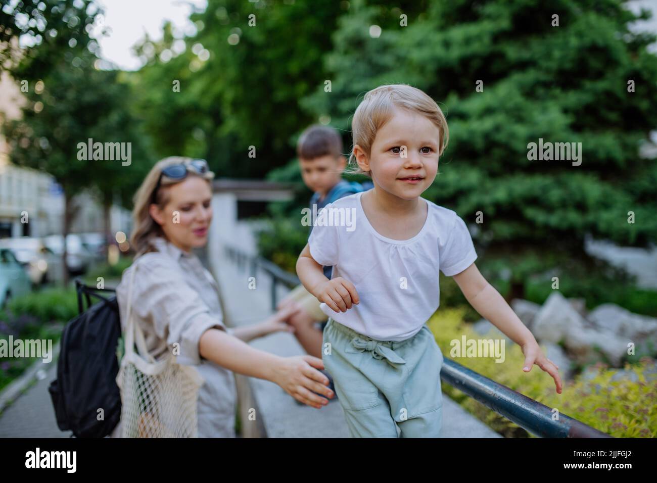Junge Mutter mit Null-Abfall-Einkaufstasche mit ihren Kindern und zu Fuß in der Stadtstraße Stockfoto