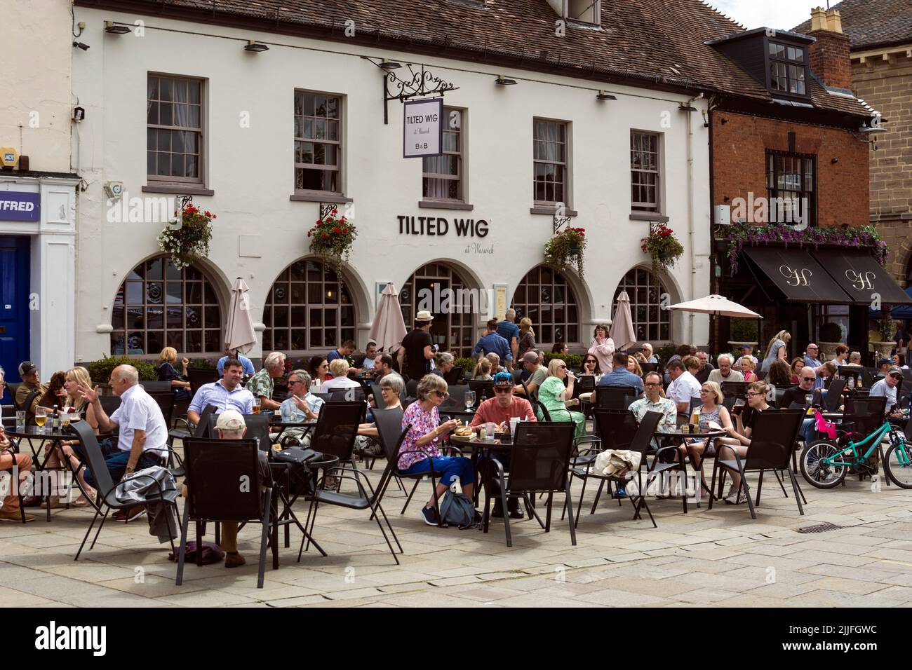Menschen saßen vor dem Pub Tilted Perig, Market Place, Warwick, Warwickshire, Großbritannien Stockfoto