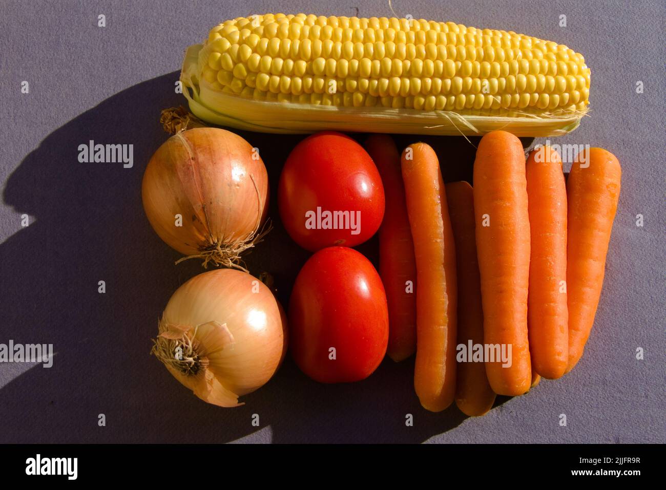 Zubereitetes Gemüse für Suppe oder gemischten Salat: Rohe Karotten, Zwiebeln, Mais, Tomaten Stockfoto