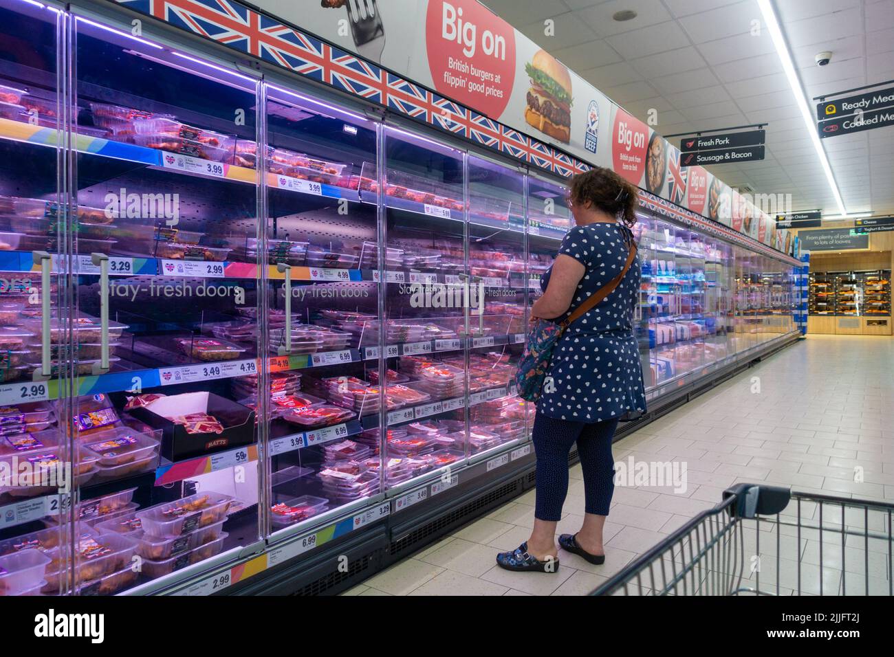 Ashford, Kent, Großbritannien. 26. Juli 2022. Lidl-Laden in Ashford, Kent, hat Schilder in den Gängen angebracht, auf denen stand: „Nur 6 Einheiten jedes Artikels pro Kunde im gesamten Laden, ähnlich wie Aldi auf seinen Flyern gedruckt hat, „aufgrund der derzeitigen Störung des globalen Versands kann es zu Verzögerungen bei einer Reihe von Sondereinkäufen kommen. Frau, die den gekühlten Fleischgang im Lidl-Laden betrachtet.Bildnachweis: Paul Lawrenson/Alamy Live News Stockfoto