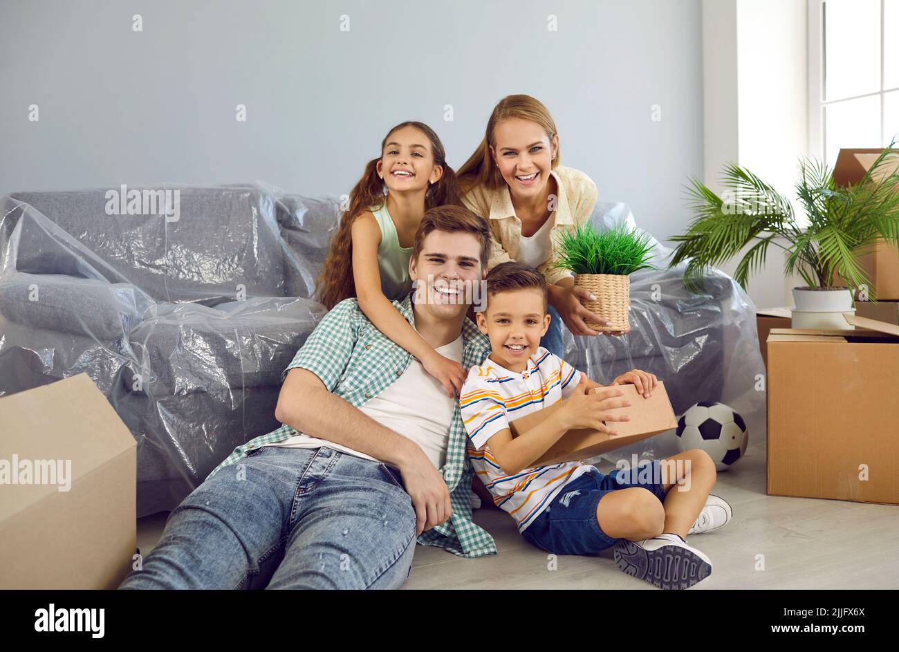 Porträt einer glücklichen Familie mit Kindern im Wohnzimmer ihres neuen Zuhauses am Umzugstag Stockfoto