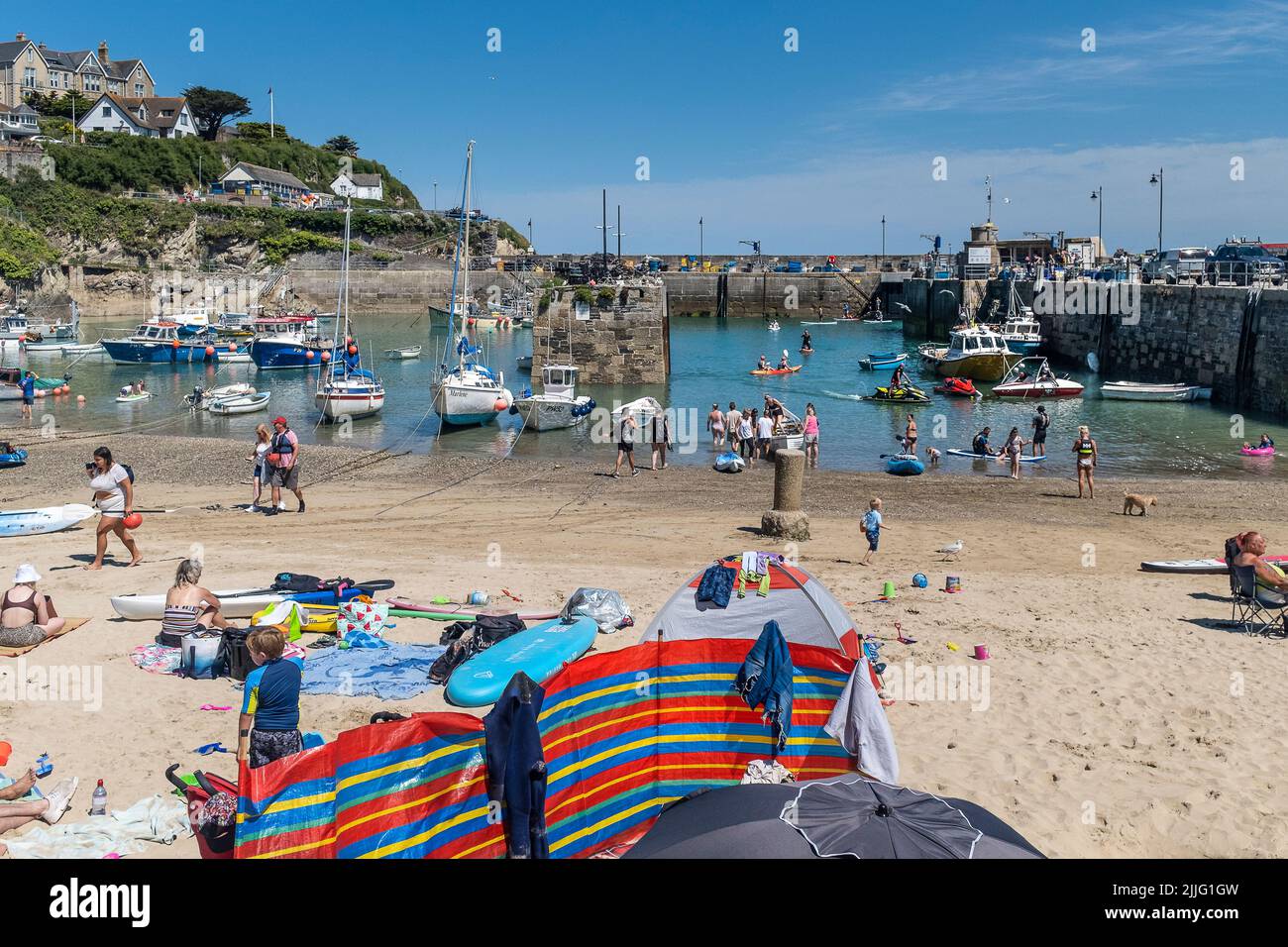 Urlauber genießen den herrlichen Sonnenschein bei einem Aufenthalt im malerischen Newquay Harbour in Cornwall in England im Vereinigten Königreich. Stockfoto