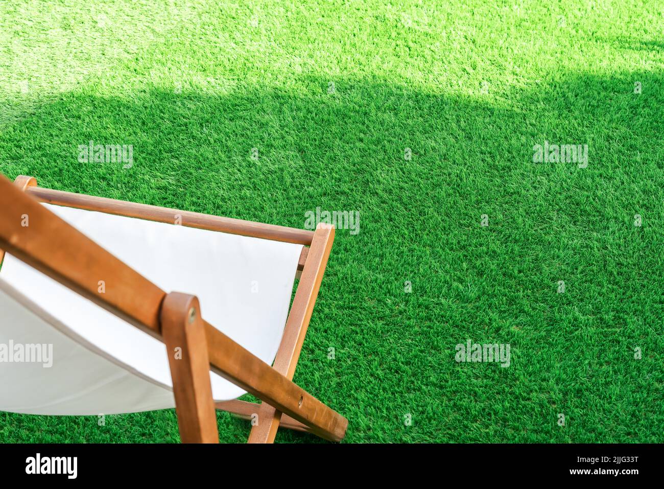 Nahaufnahme einer Sonnenliege auf einem Kunstrasen. Grüne Rasenfläche, ideal für Terrassen, Schwimmbäder oder Gärten Stockfoto