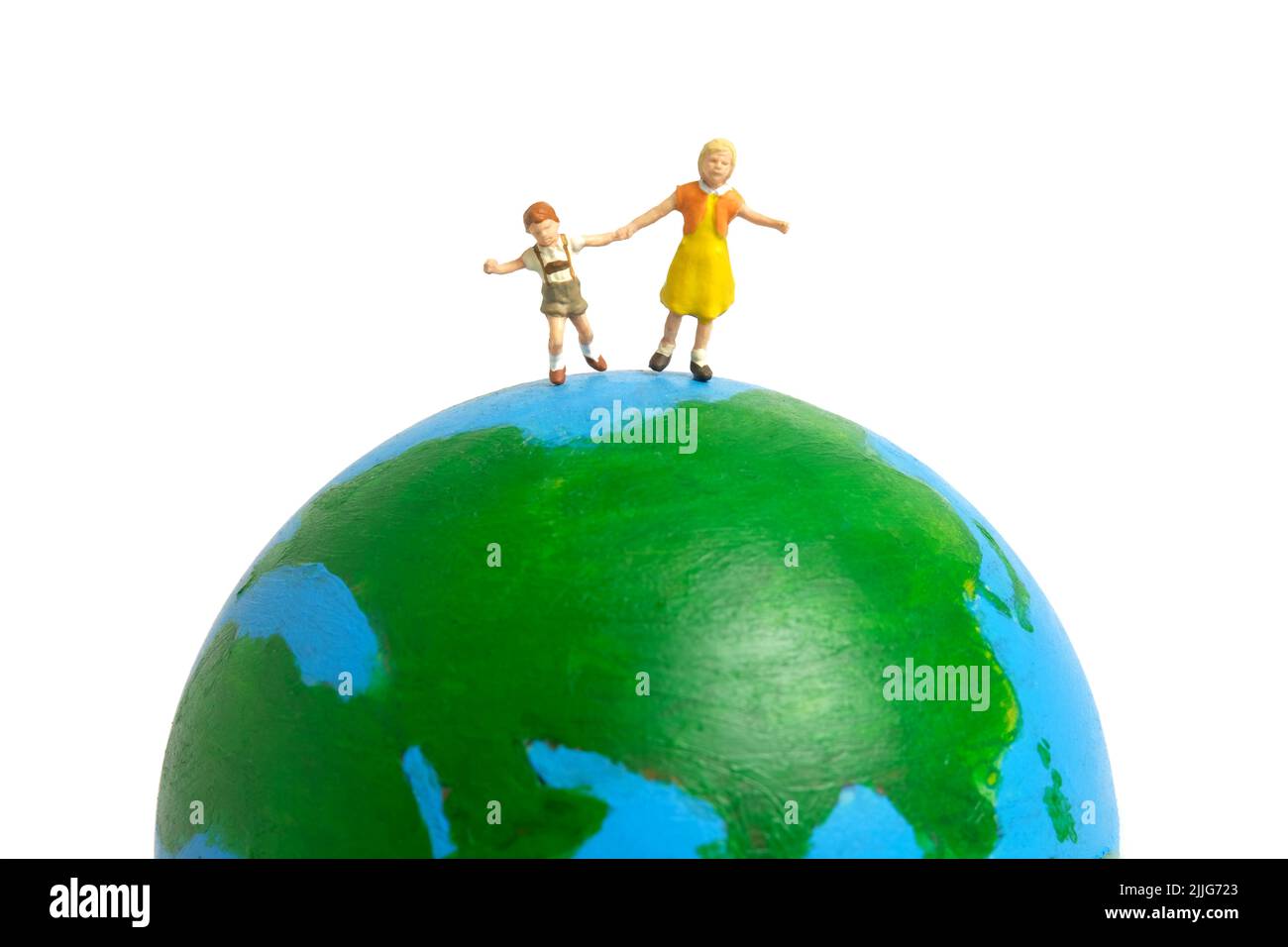 Miniatur Menschen Spielzeug Figur Fotografie. Konzept für den internationalen Kindertag. Eine Gruppe von Kindern, die über der Erde spielen, isoliert auf weißem Hintergrund. Imag Stockfoto