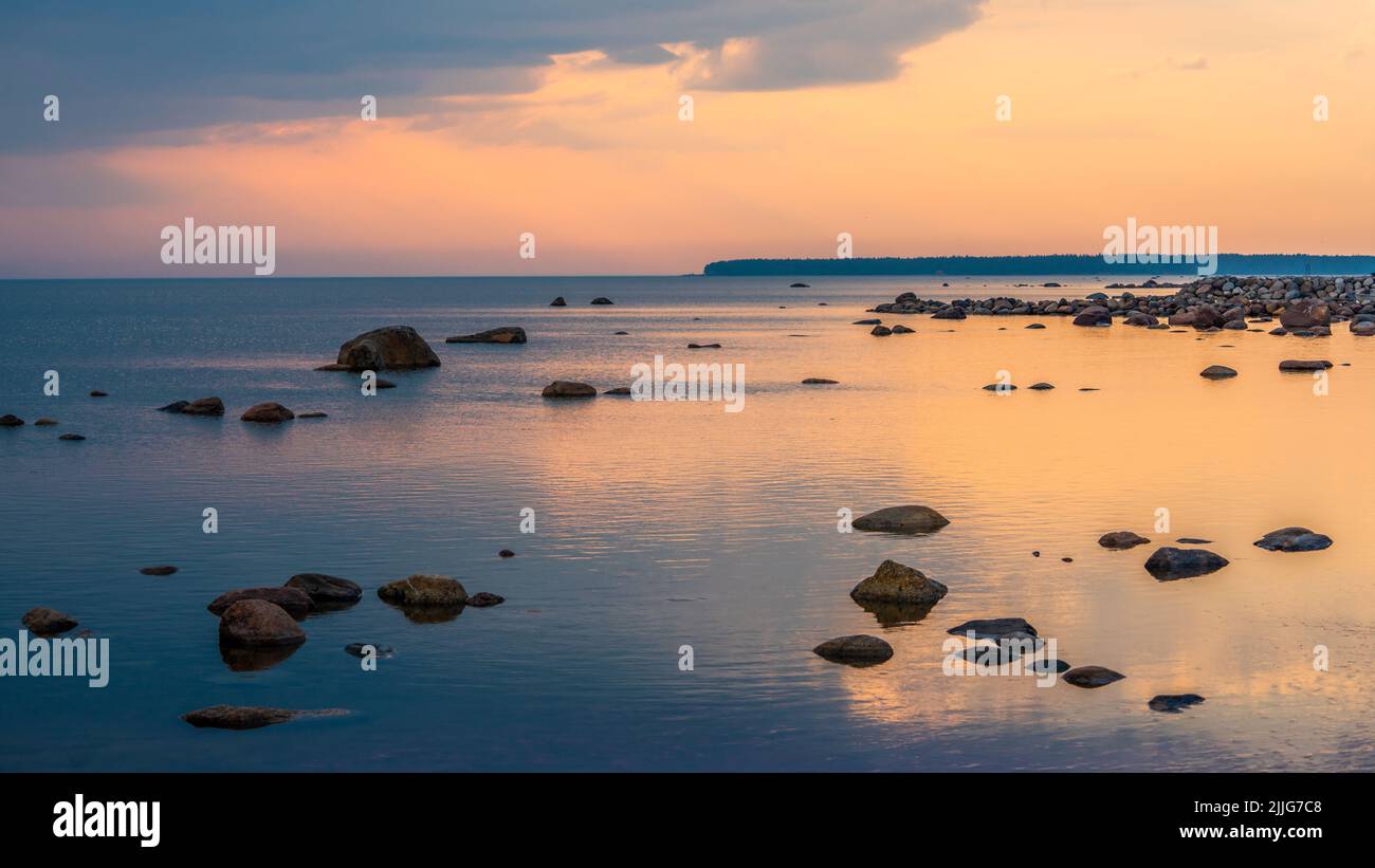 Wunderschöne Strandbrocken in einer ruhigen Ostsee während eines gelben bunten Sonnenuntergangs in der Nähe von Tallinn City. Stockfoto