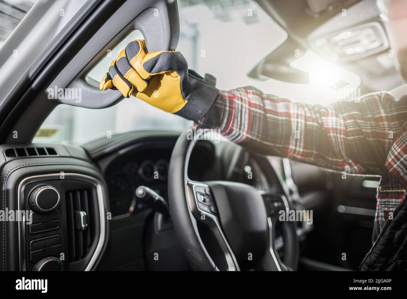 Nahaufnahme einer Männerhand in gelben Arbeitshandschuhen, die sich beim Aussteigen am Griff halten. Stockfoto