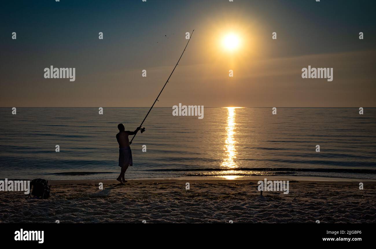 Ein einesker Fischer wirft seine Rute in der Morgendämmerung vom Strand in der Nähe von Port El Kantaoui in Tunesien. Stockfoto