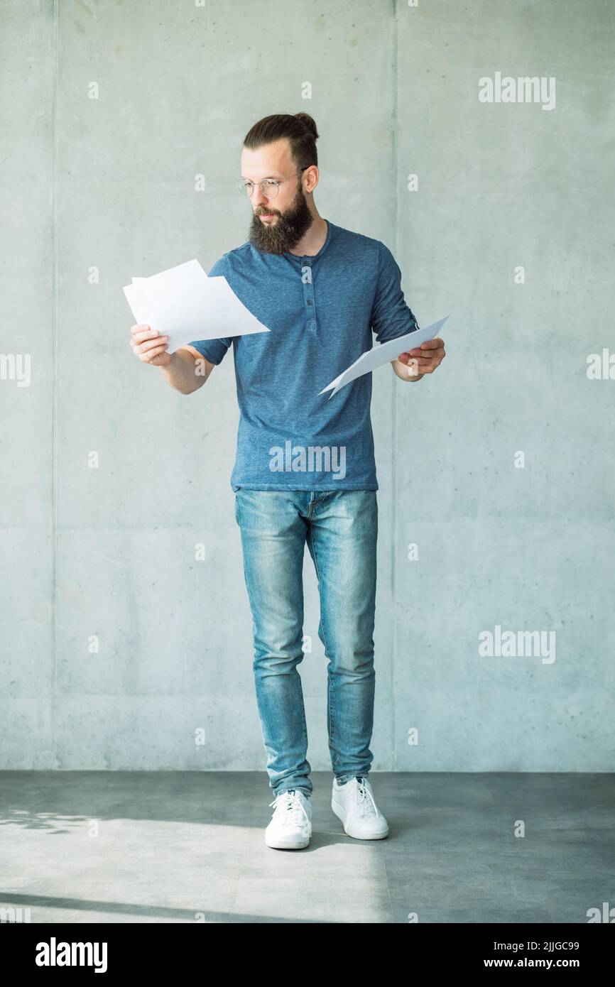 Mann beim Lesen von Skriptpapieren mit Schwerpunkt auf Bildschirmschreiber Stockfoto