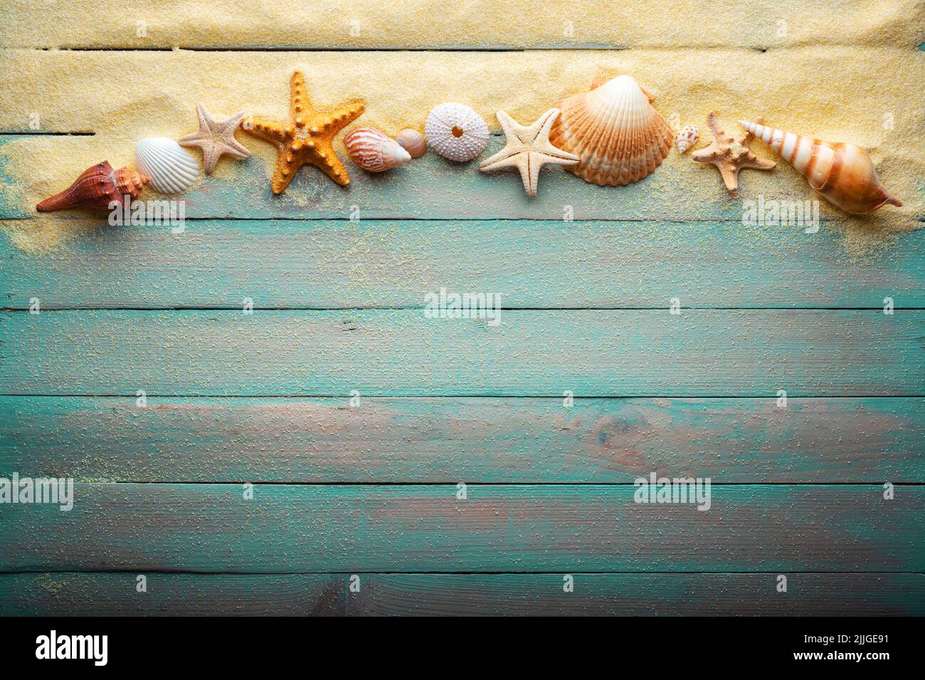 Ferien- und Sommerzeitkonzept mit Seesternen und Muscheln auf einem türkisfarbenen Holztisch mit Sand Stockfoto