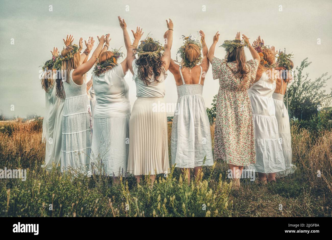 Frauen im Blumenkranz auf sonniger Wiese, Blumenkrone, Symbol der Sommersonnenwende. Stockfoto