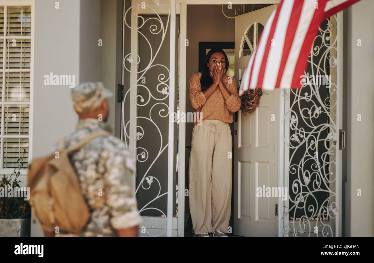 Überraschte Militärfrau, die ihren Mann aus der Armee willkommen hieß. Patriotischer junger Militärangehöriger, der sich mit seiner Frau wiedervereinigt, nachdem er seinem Land in der Milit gedient hatte Stockfoto