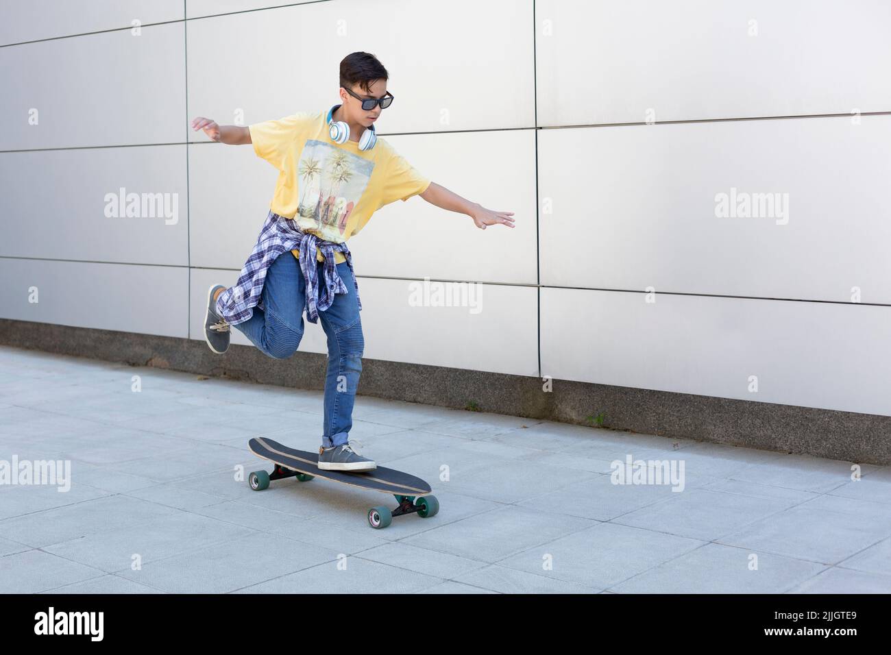 Kaukasischer Teenager, der auf der Straße langes Skateboard reitet. Urbane Lebensart. Platz für Text. Stockfoto
