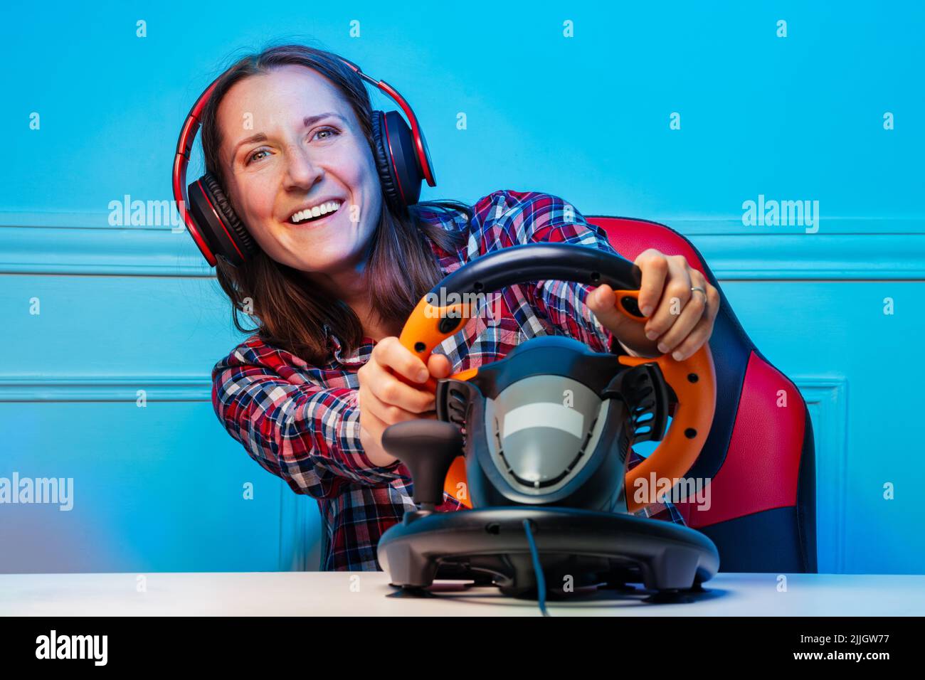 Gamer Frau in Kopfhörer spielen Rennspiel mit Lenkrad Stockfoto