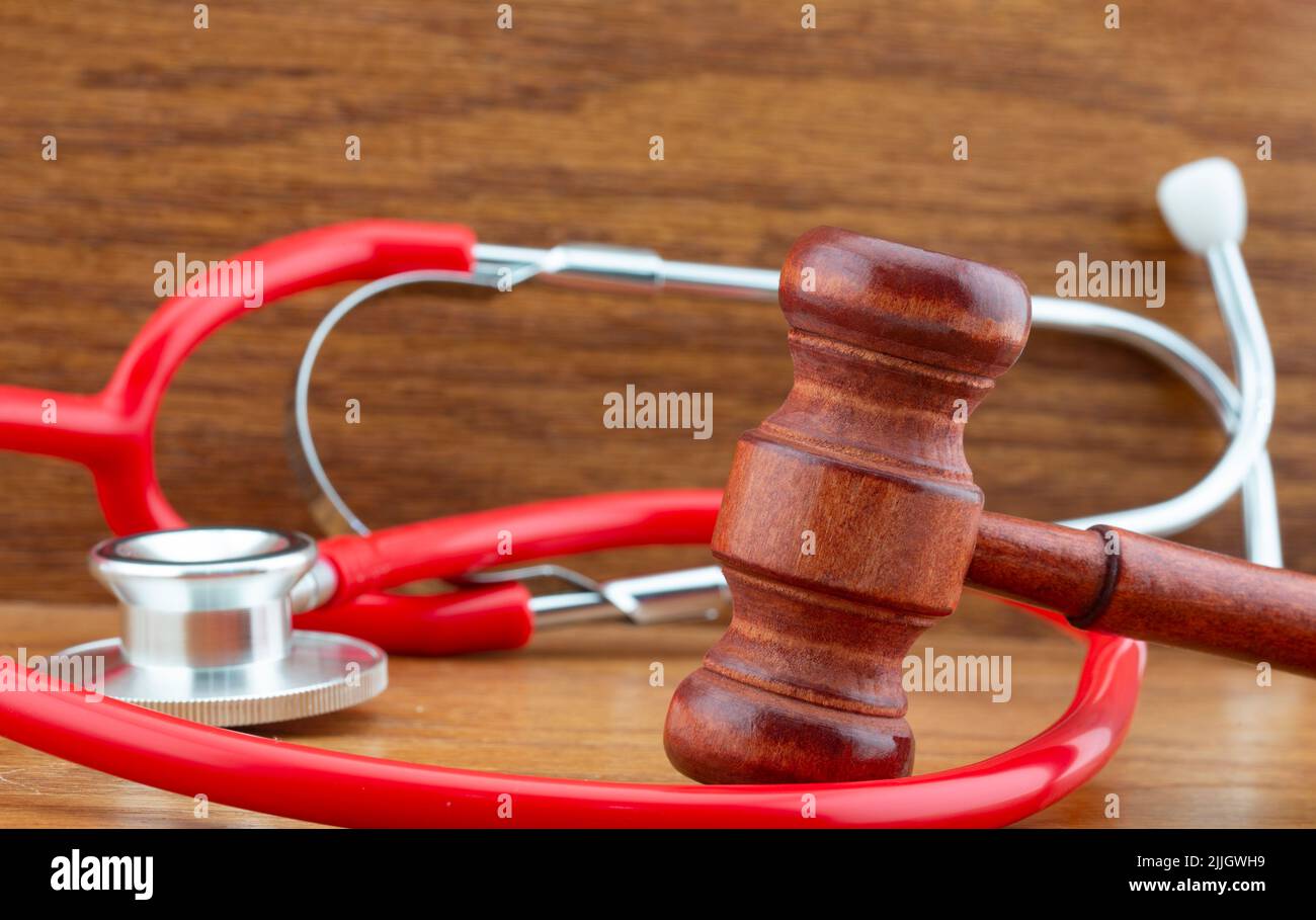 Holzgavel und rotes Stethoskop sind Symbole für Entscheidungen in den Bereichen Recht, Privates und Medizin in Medizin, Politik und Wirtschaft Stockfoto