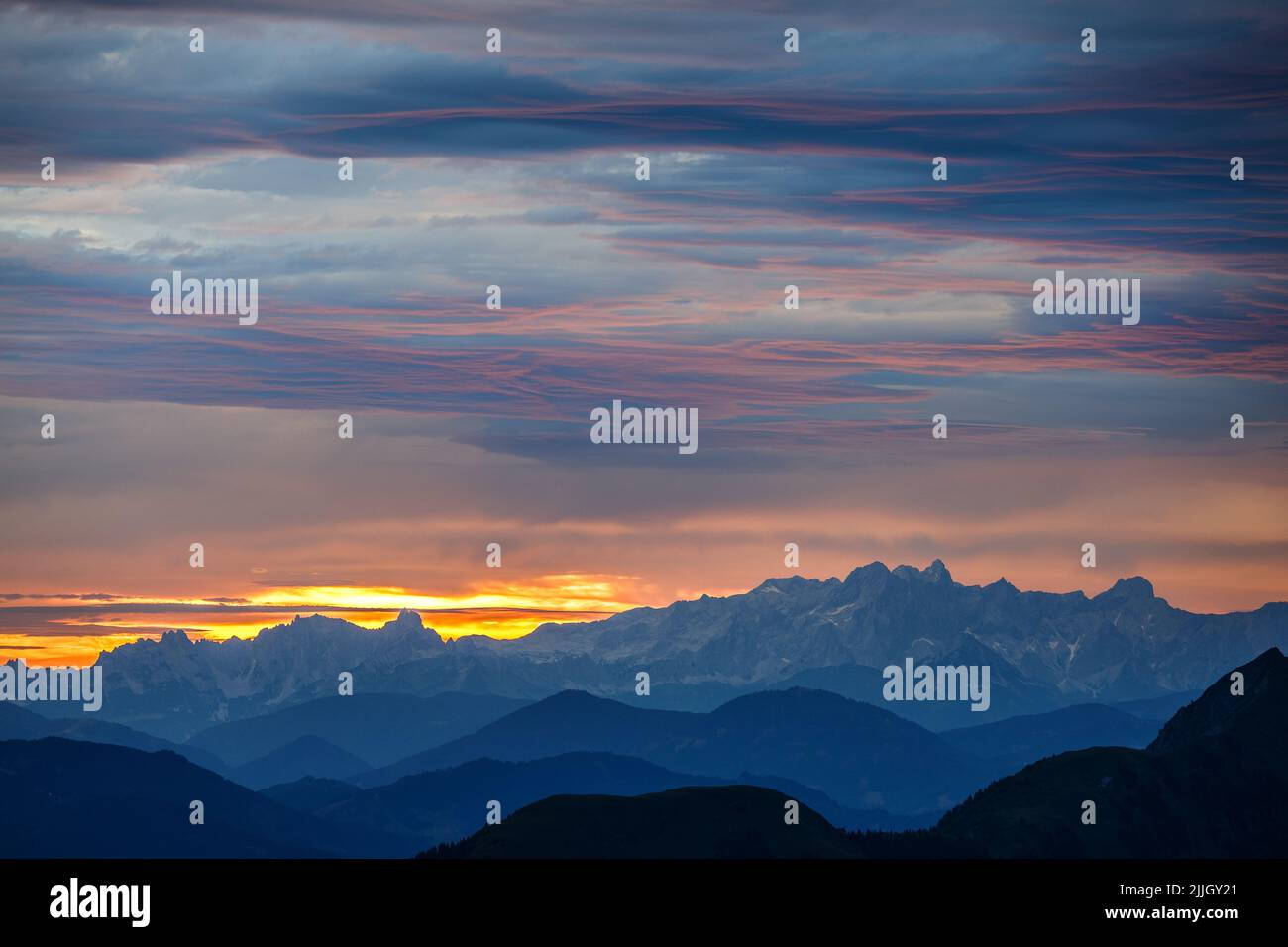 Bergprofile im Morgengrauen. Wolken durch Sonnenlicht gefärbt. Blick auf die Gipfel des Hohen Dachsteins. Österreichische Alpen. Europa. Stockfoto