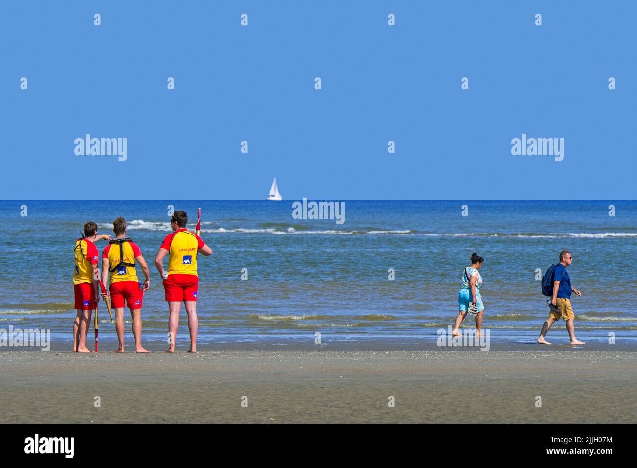 Drei junge belgische Rettungsschwimmer, die im Sommer in Koksijde / Coxyde, Westflandern, Belgien, über dem leeren Meer entlang der Nordseeküste wachen Stockfoto