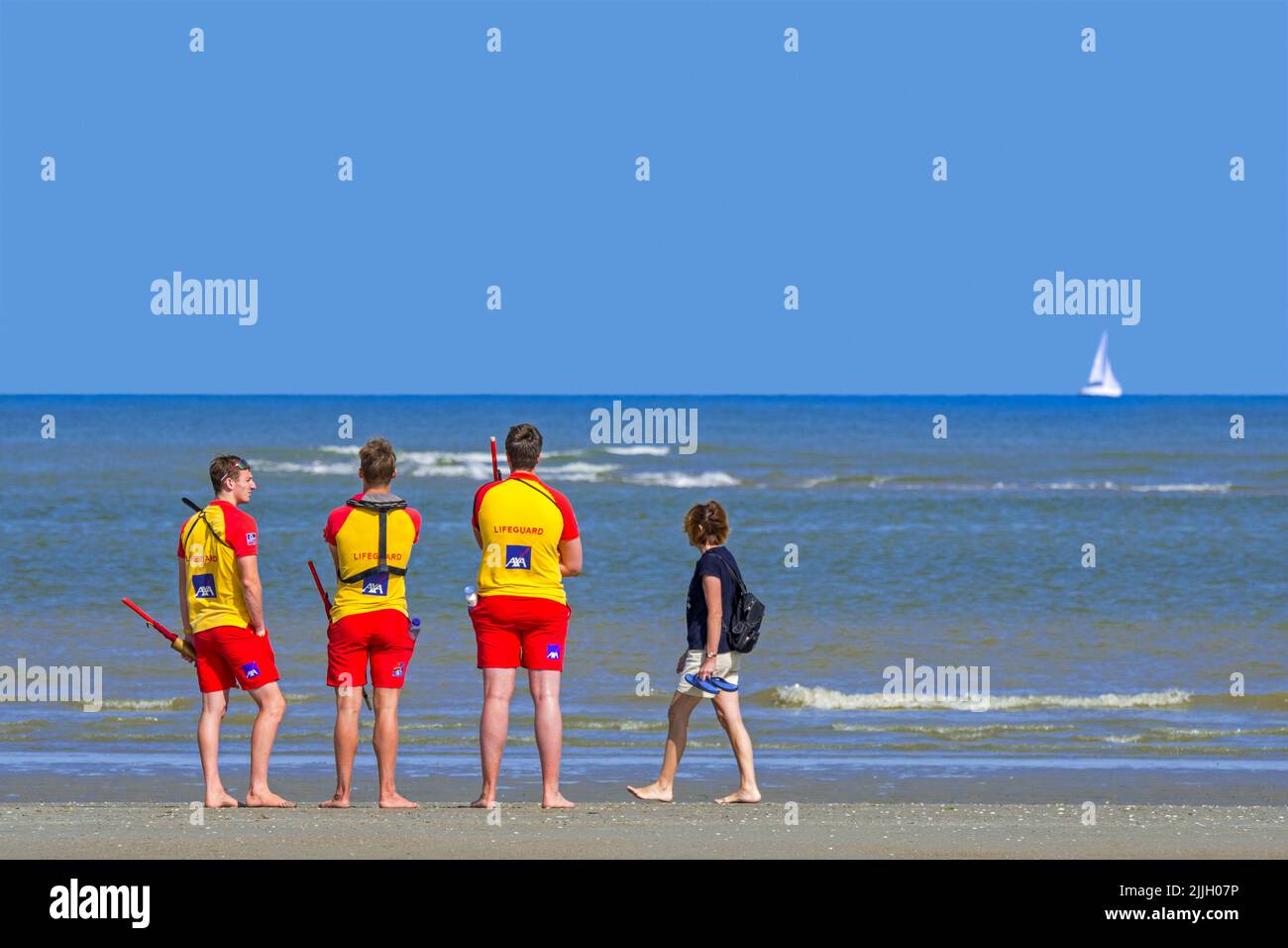 Drei junge belgische Rettungsschwimmer, die im Sommer in Koksijde / Coxyde, Westflandern, Belgien, über dem leeren Meer entlang der Nordseeküste wachen Stockfoto