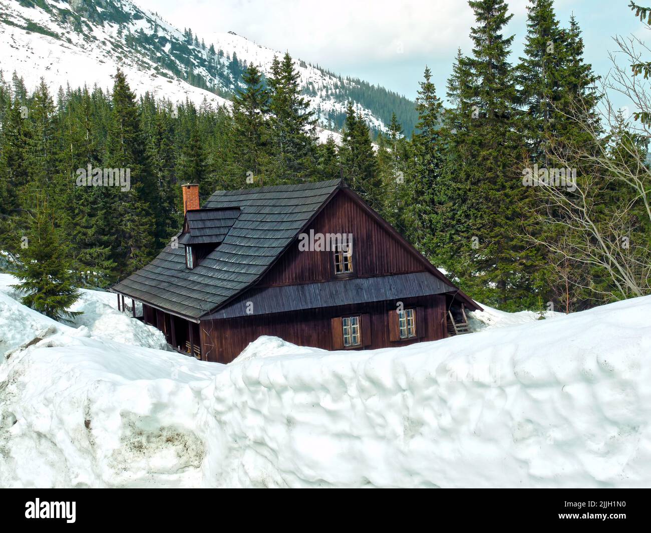 Berghütte aus Holz unter dichter Schneedecke nach starkem Schneefall Stockfoto