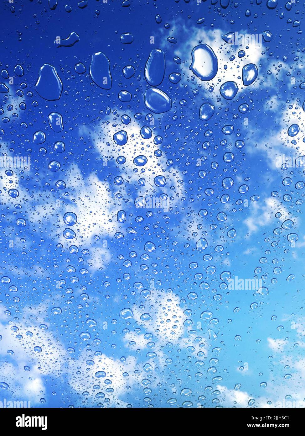 Eine vertikale Aufnahme von Wassertropfen des Regens auf dem Fenster unter einem bewölkten Himmel Stockfoto