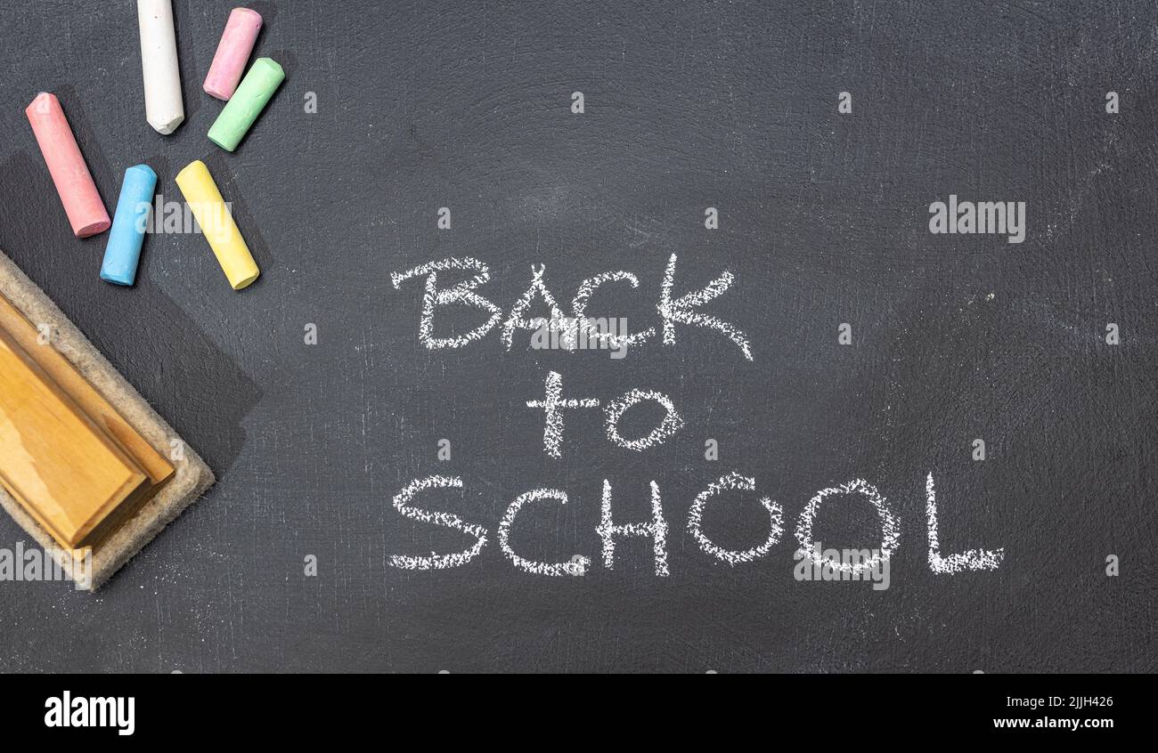 Gruppe von farbigen Kreiden, Radiergummi und handgezeichneter Phrase Back to School auf Tafel Stockfoto