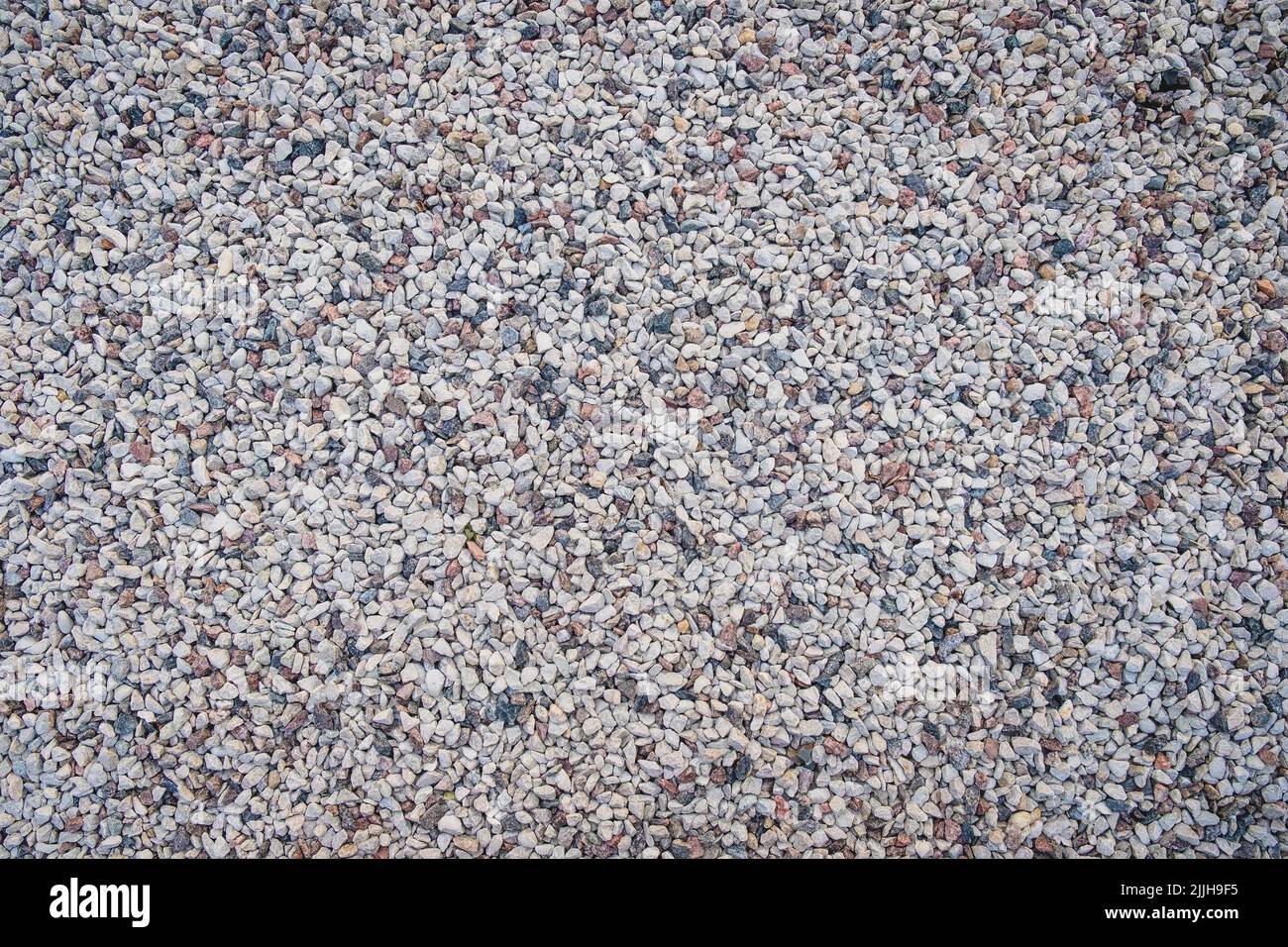 Gemischte kleine graue gebrochene Felsen, lockerer Kies, Straßenbau. Kalksteinaggregat. Hintergrund aus zerkleinertem Stein Stockfoto