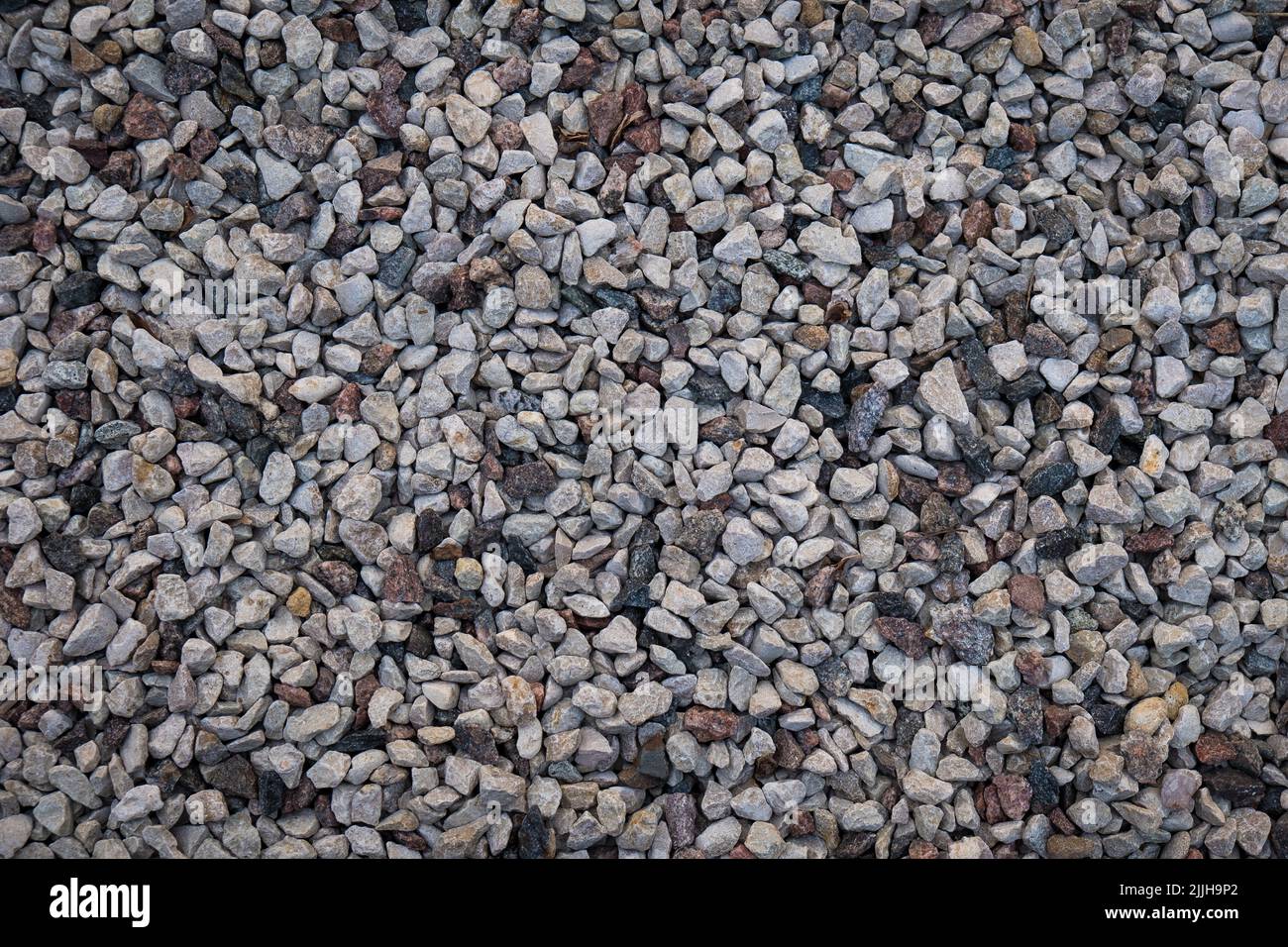 Gemischte kleine graue gebrochene Felsen, lockerer Kies, Straßenbau. Kalksteinaggregat. Hintergrund aus zerkleinertem Stein Stockfoto