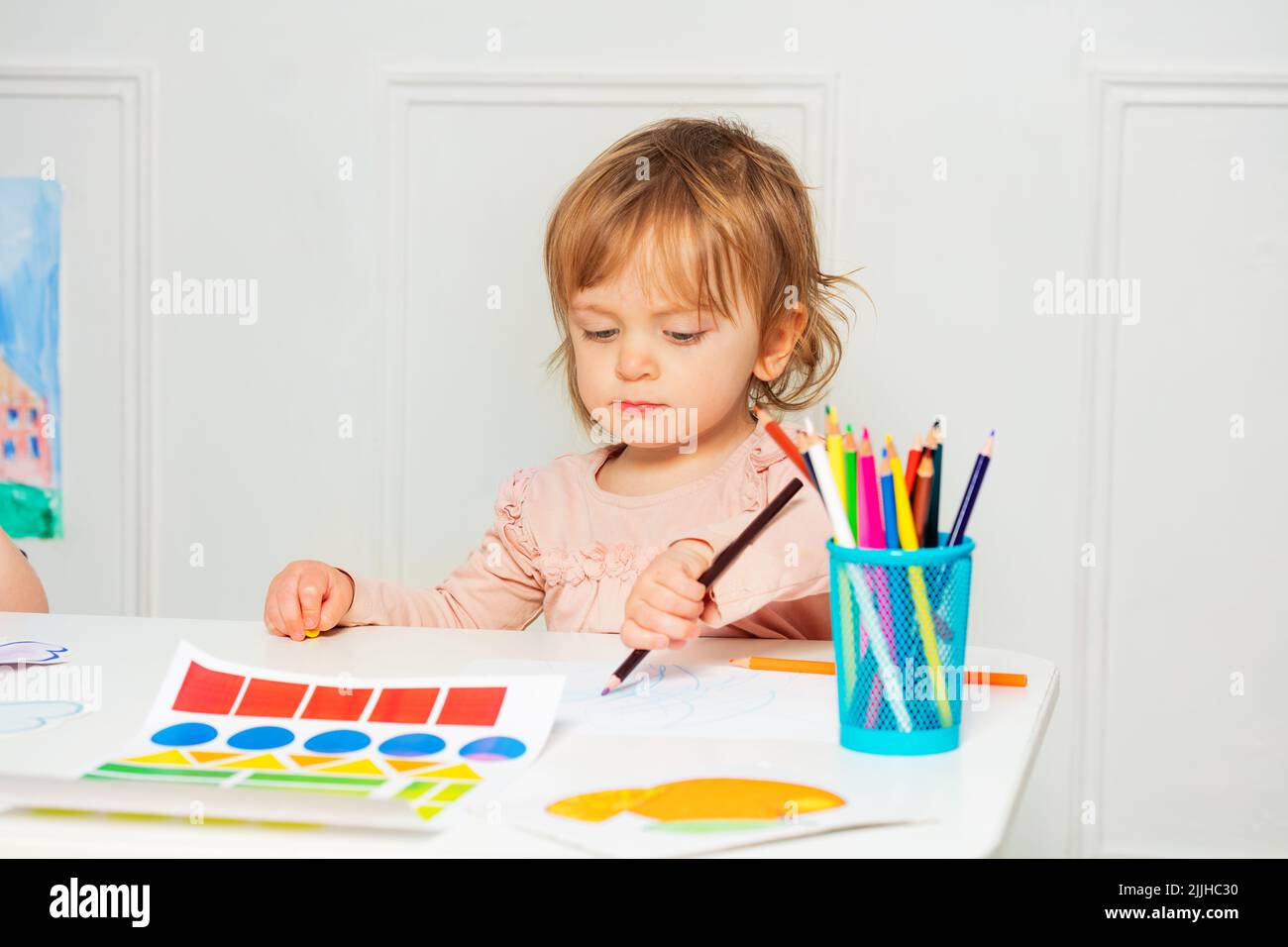 Kleines Mädchen sitzen am Tisch und zeichnen Bild mit Bleistift Stockfoto