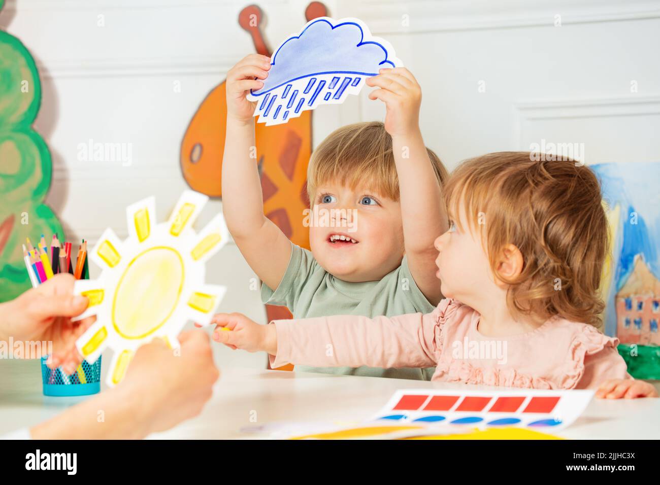 Junge, Mädchen in der Klasse spielen mit Wetter Regen und Sonnenkarten Stockfoto