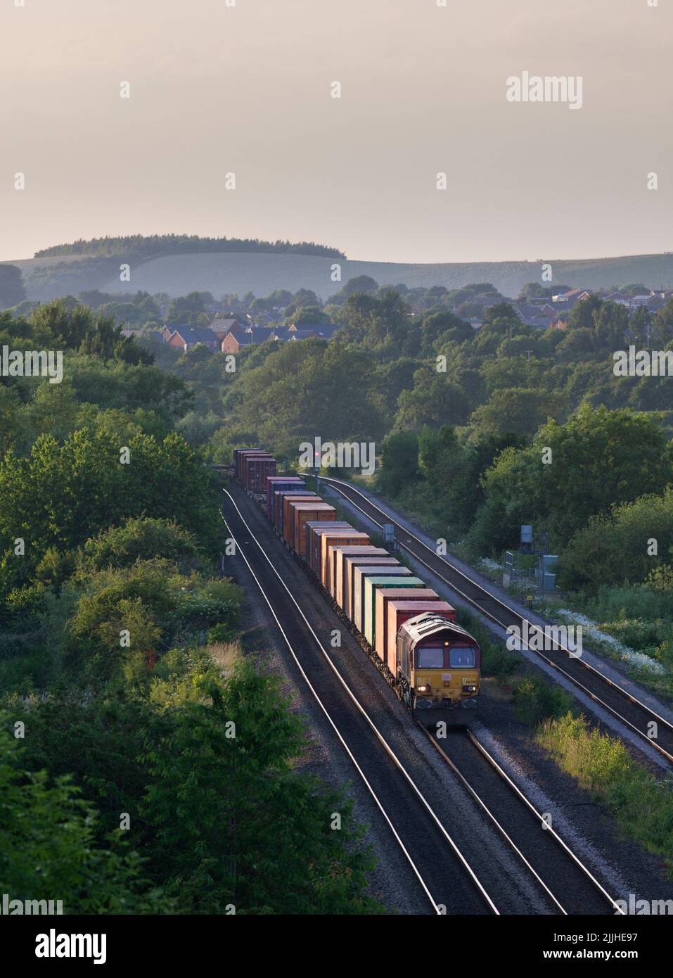 DB Cargo Rail UK Diesellokomotive der Baureihe 66, die Bennerley im Erewash Valley, Nottinghamshire, Großbritannien, mit einem Güterzug mit Containern passiert Stockfoto