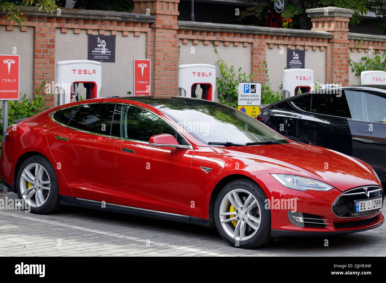 Posen, Polen. 26 Jul 2022: Ein roter Tesla beim Laden an der Supercharger Station. Der Supercharger bietet schnelles Laden für Elektrofahrzeuge. Stockfoto