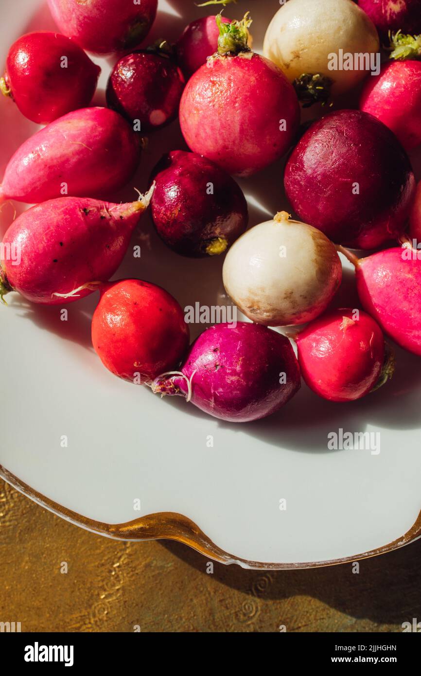 Getrimmt rosa, rot, lila, weiße Radieschen auf weißem Teller mit Gold Stockfoto