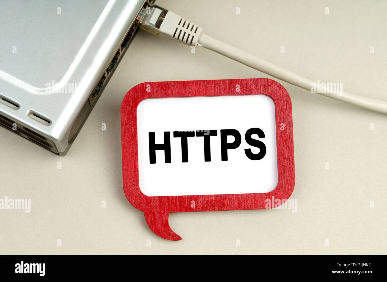 Internet- und Sicherheitskonzept. Auf dem Tisch befindet sich ein Router, der mit dem Netzwerk verbunden ist, neben einem Schild mit der Aufschrift HTTPS Stockfoto