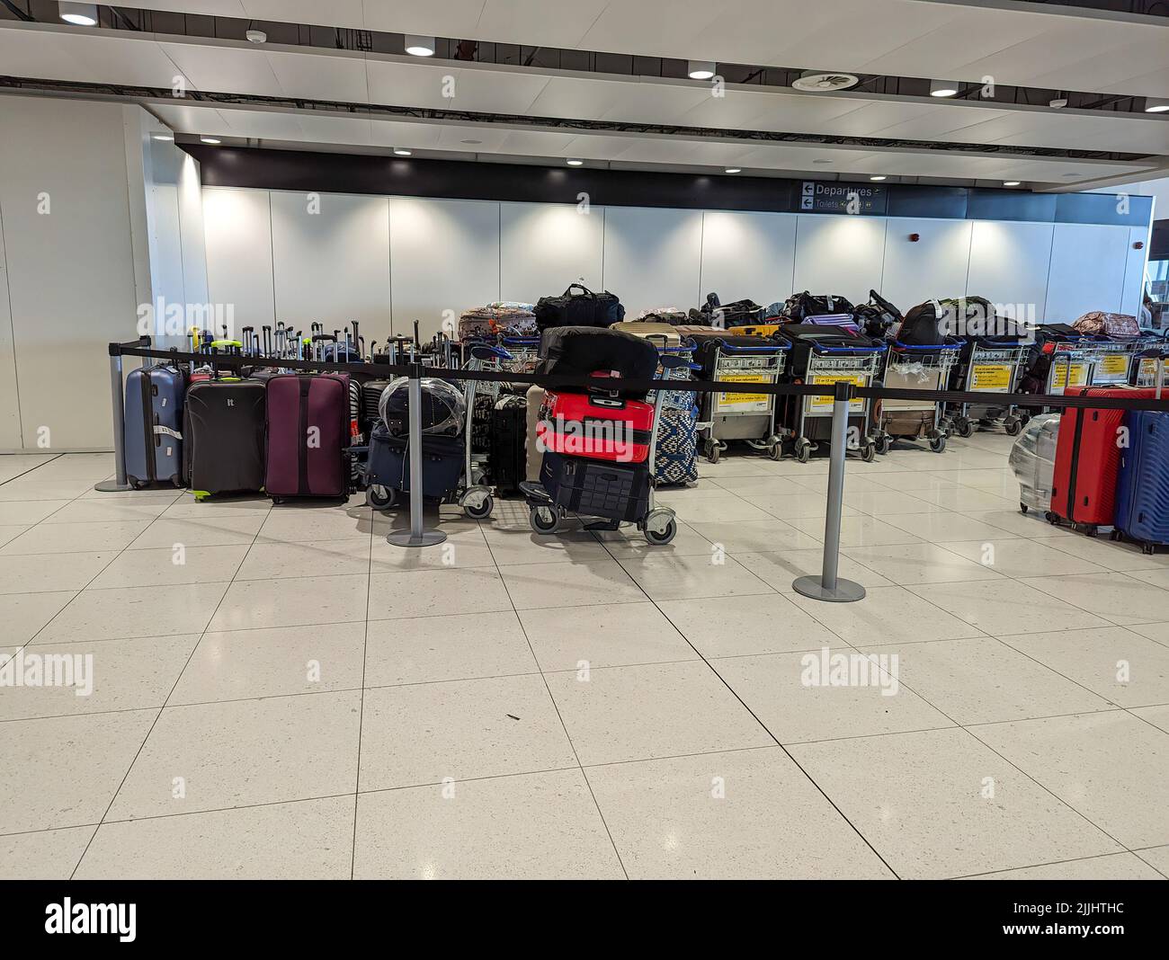 MANCHESTER, VEREINIGTES KÖNIGREICH - JULI 24. 2022: Stapel verspäteter Gepäckstücke warten am Flughafen von Manchester Stockfoto