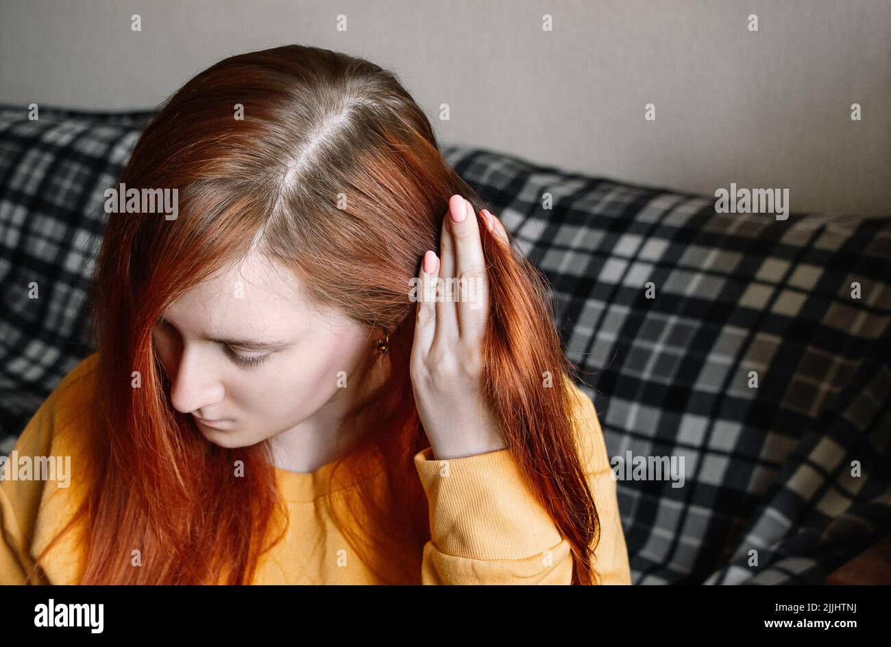 Junge Frau zeigt überwuchert Haarwurzeln. Selbstpflege-Konzept, Haarfärbung zu Hause. Erstes graues Haar. Stockfoto