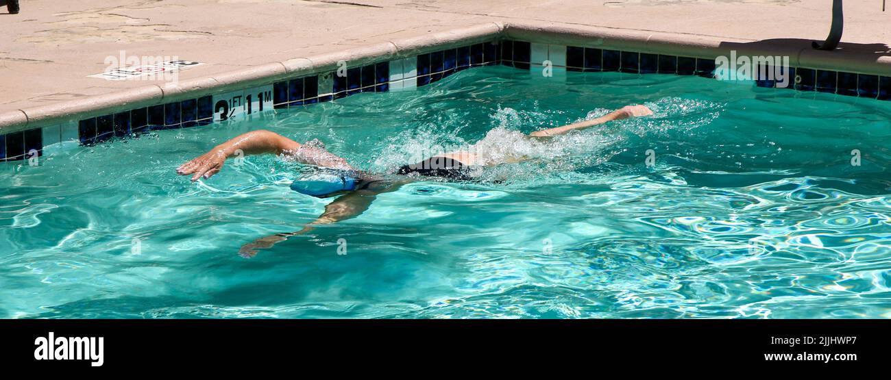 Eine Frau im Urlaub schwimmt in ihrem Hotelpool Bahnen. Stockfoto