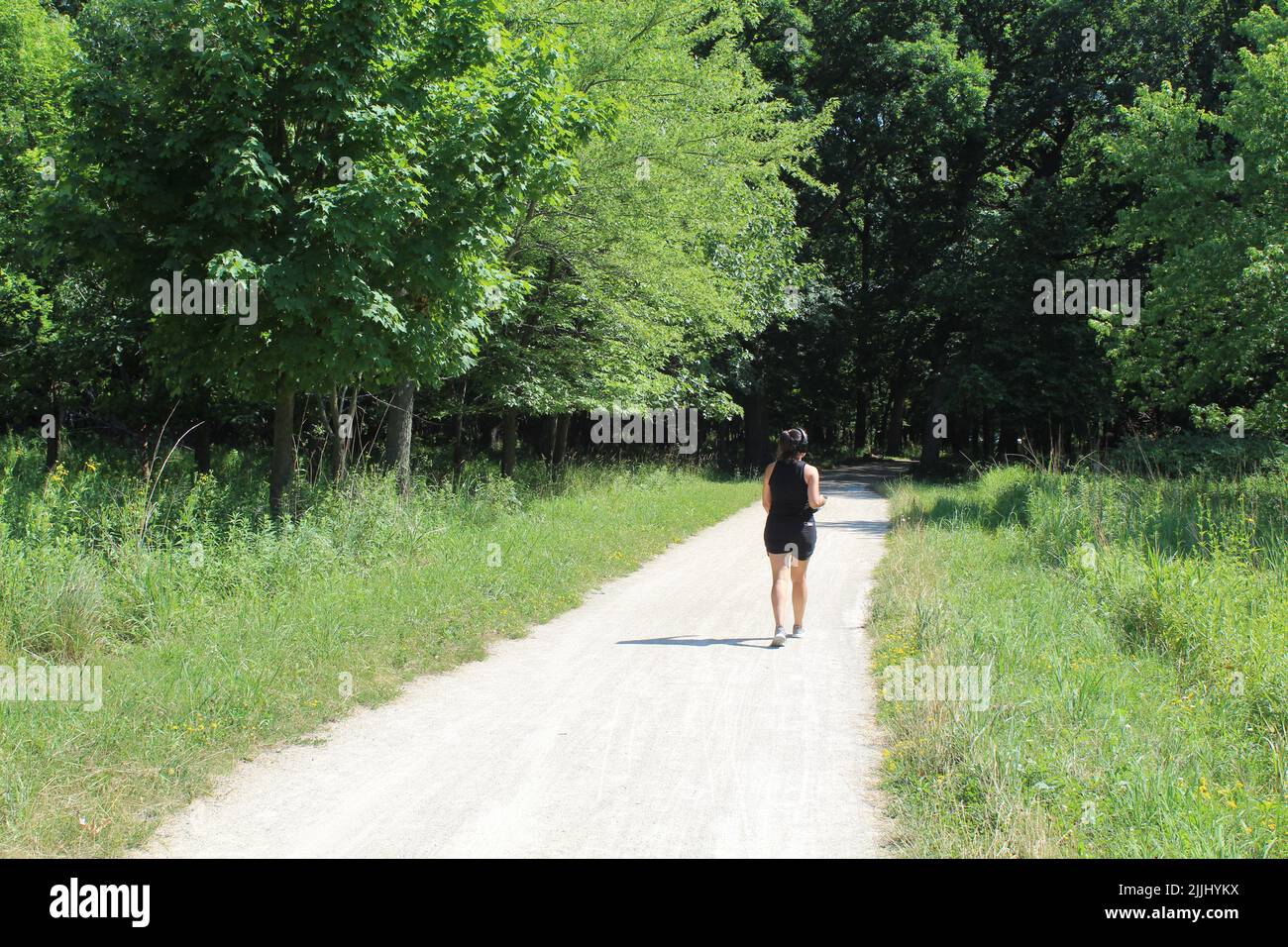 Junge Frau mit Kopfhörern auf dem des Plaines River Trail in den Iroquois Woods in Park Ridge, Illinois Stockfoto