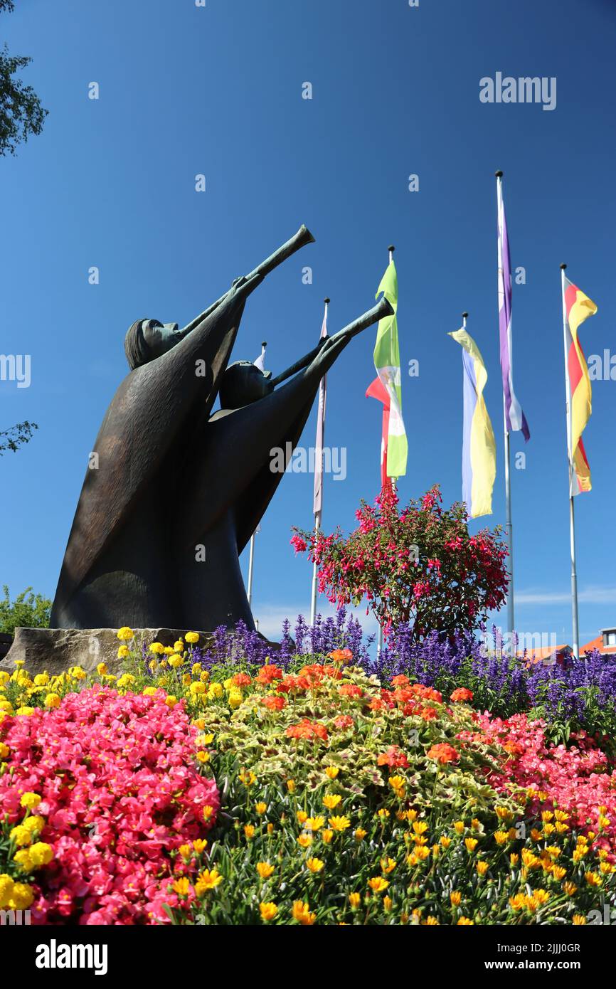 Statue als Trompetenspieler. Im Sommer mit blauem Himmel und Blumen. Gesehen im allgäuer öffentlichen Park Stockfoto