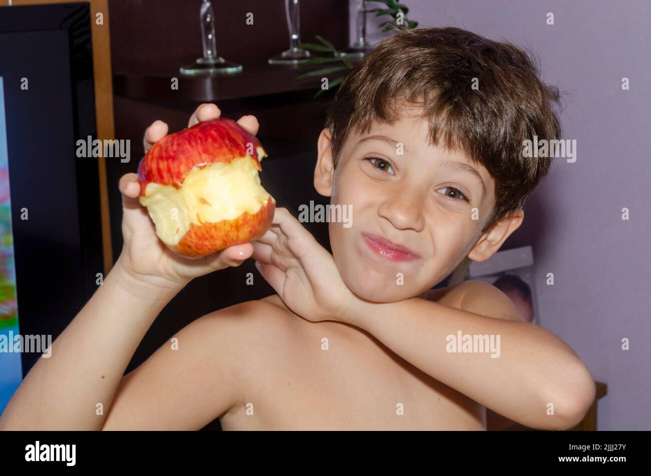 Kind, das zu Hause roten Apfel isst. Salvador, Bahia, Brasilien. Stockfoto