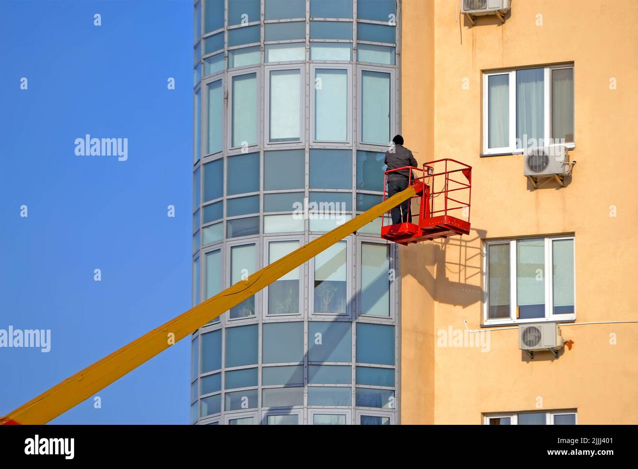 Unbekannter Mann in roter Konstruktion Wiege Befestigung des Glasfensters auf dem Gebäude in Kiew, Ukraine. Stockfoto