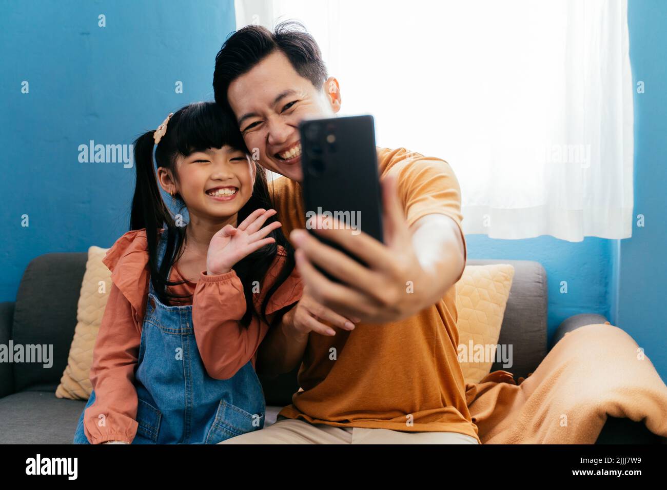 Asiatische Familie von Vater und Tochter, die ein Selfie-Foto mit Handy zu Hause Stockfoto