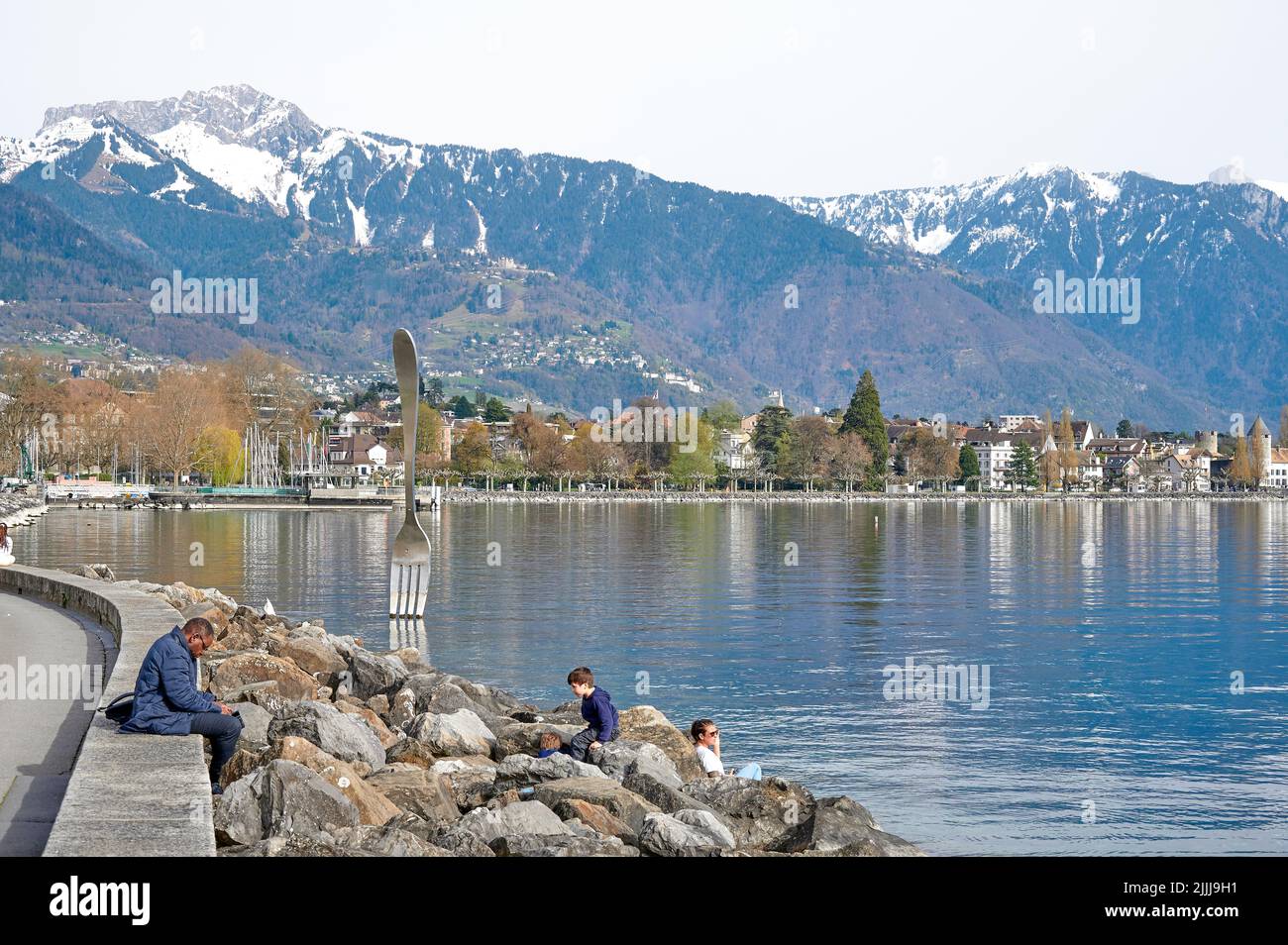 Vevey, Schweiz - 12. April 2022: Menschen entspannen sich an der Fork-Skulptur vor dem Alimentarium-Museum am Ufer des Genfer Sees. Stockfoto