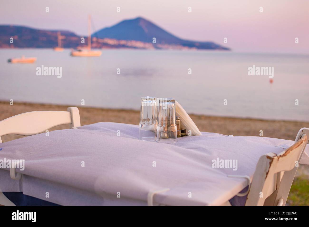 Typisch griechischer Tavernentisch am Meer mit Holzstühlen an der Küste von Gialova in der Nähe von Pylos, Messinia, Griechenland, Europa Stockfoto