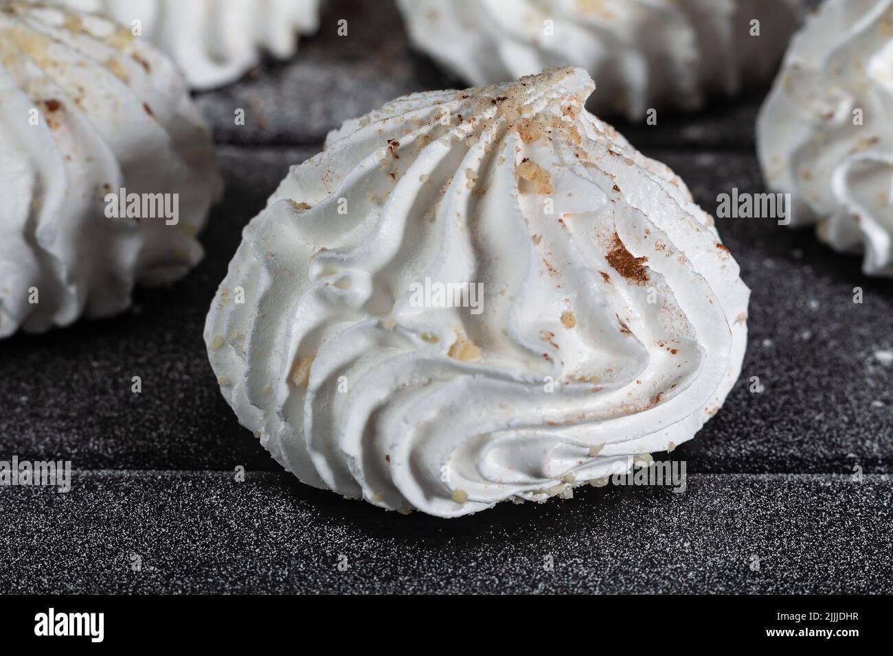 Nahaufnahme französischer Meringues mit Nüssen, zubereitet aus mit Zucker gepeitschten und gebackenen Eiern auf dunklem Holztisch. Seitenansicht, selektiver Fokus Stockfoto